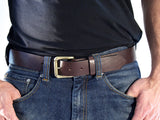 Brown leather belt with a removable gold buckle and a belt loop worn with blue jeans.